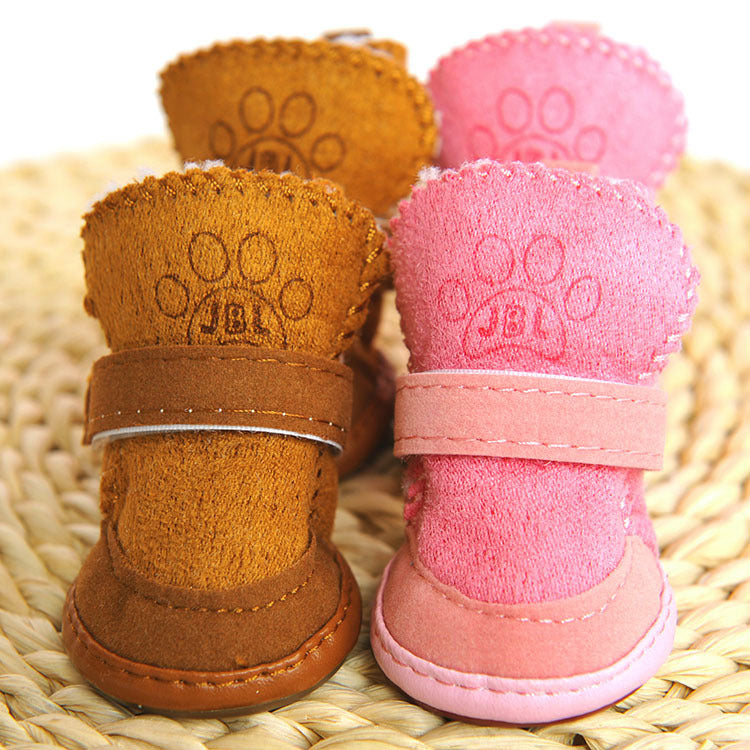 Pair of brown and pink pet boots with paw prints on a woven surface